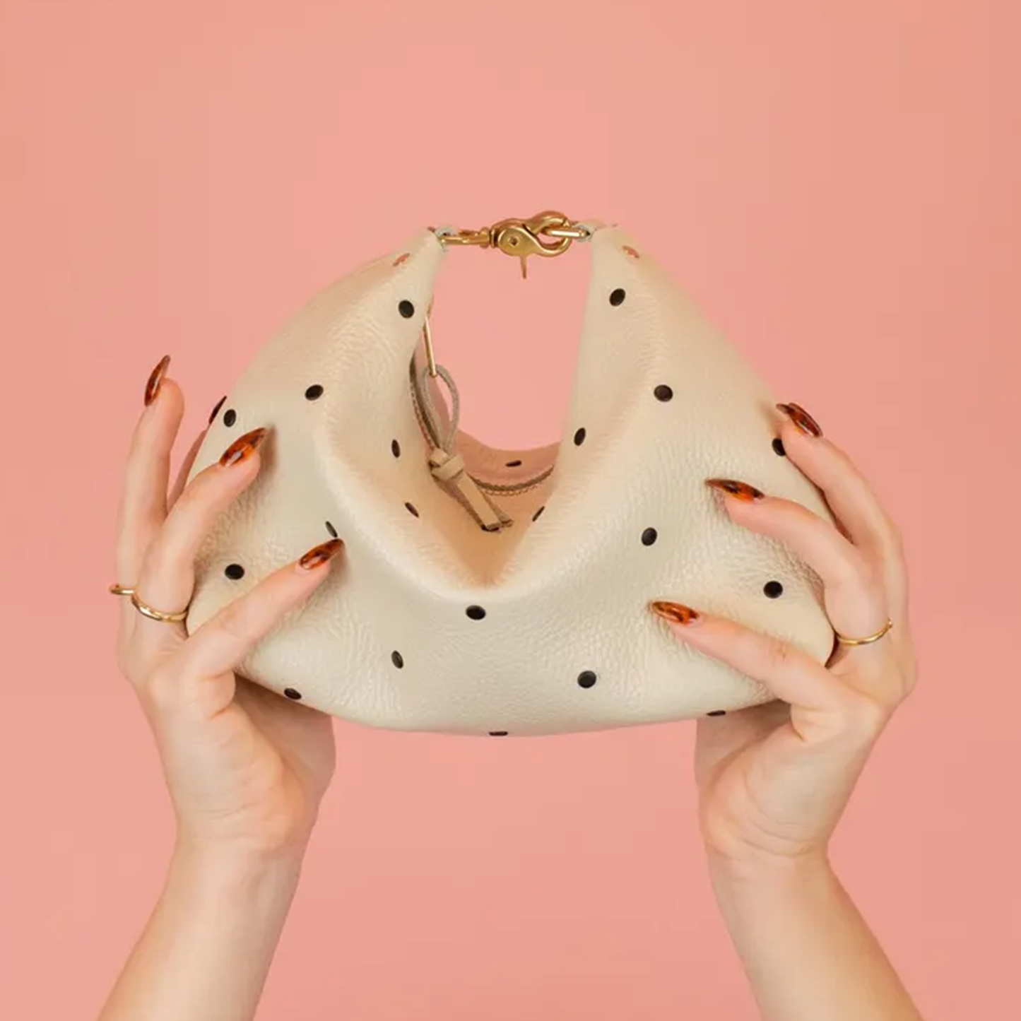 Creamy Off-White Curved Slouchy Pouch With Even Black Dot Motifs, Polished Warm Gold Hardware And Thin Matching Wrist Carry Strip