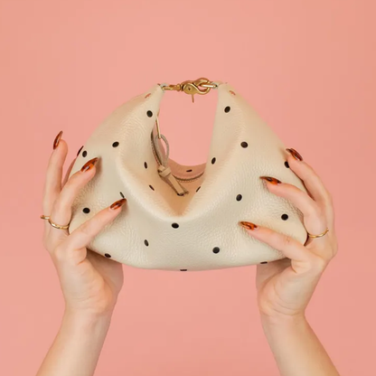 Creamy Off-White Curved Slouchy Pouch With Even Black Dot Motifs, Polished Warm Gold Hardware And Thin Matching Wrist Carry Strip