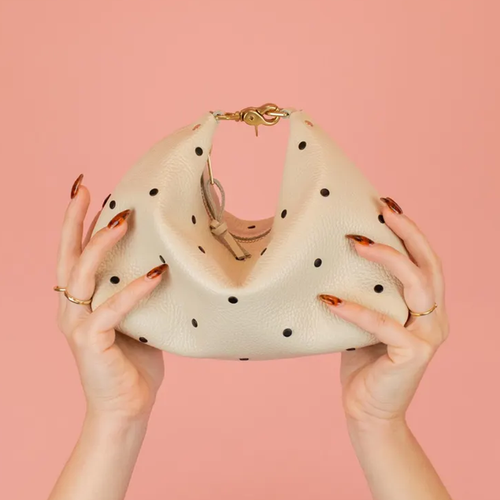 Creamy Off-White Curved Slouchy Pouch With Even Black Dot Motifs, Polished Warm Gold Hardware And Thin Matching Wrist Carry Strip