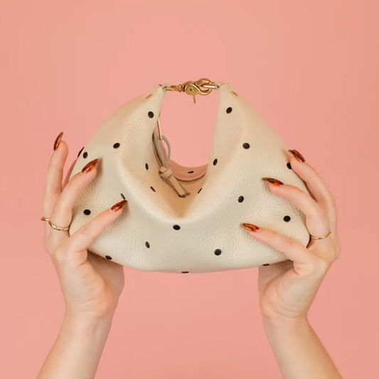 Creamy Off-White Curved Slouchy Pouch With Even Black Dot Motifs, Polished Warm Gold Hardware And Thin Matching Wrist Carry Strip