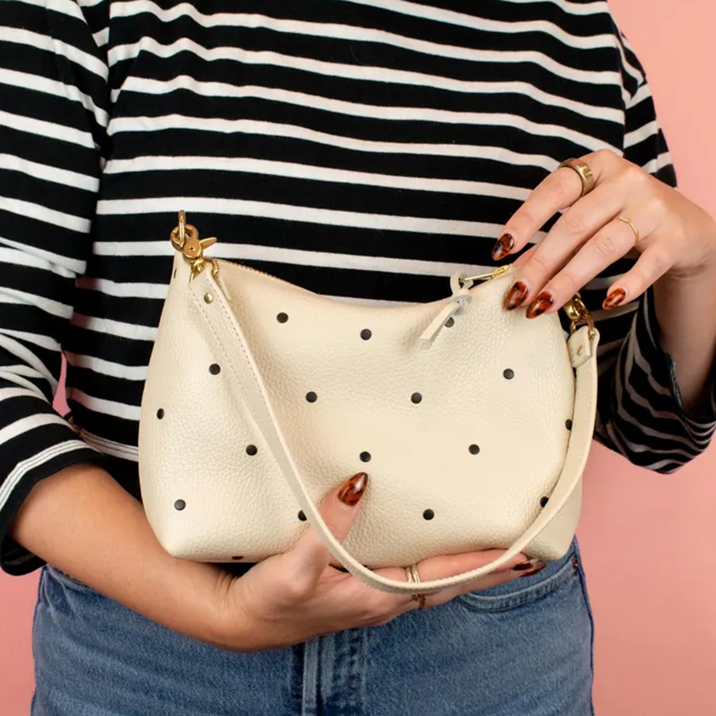 Creamy Off-White Curved Slouchy Pouch With Even Black Dot Motifs, Polished Warm Gold Hardware And Thin Matching Wrist Carry Strip
