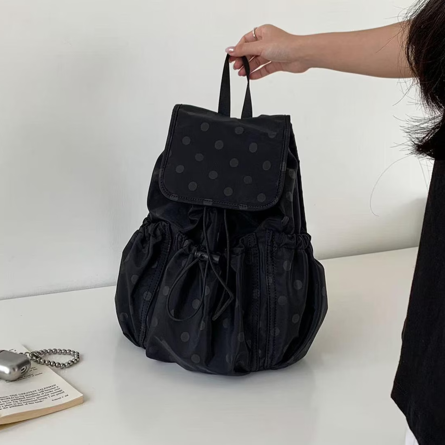 Solid Black Subtle Dot Pattern Slouchy Drawstring Rucksack With Square Overlay Flap, Ruched Side Storage Panels And Compact Fabric Top Carry Loop